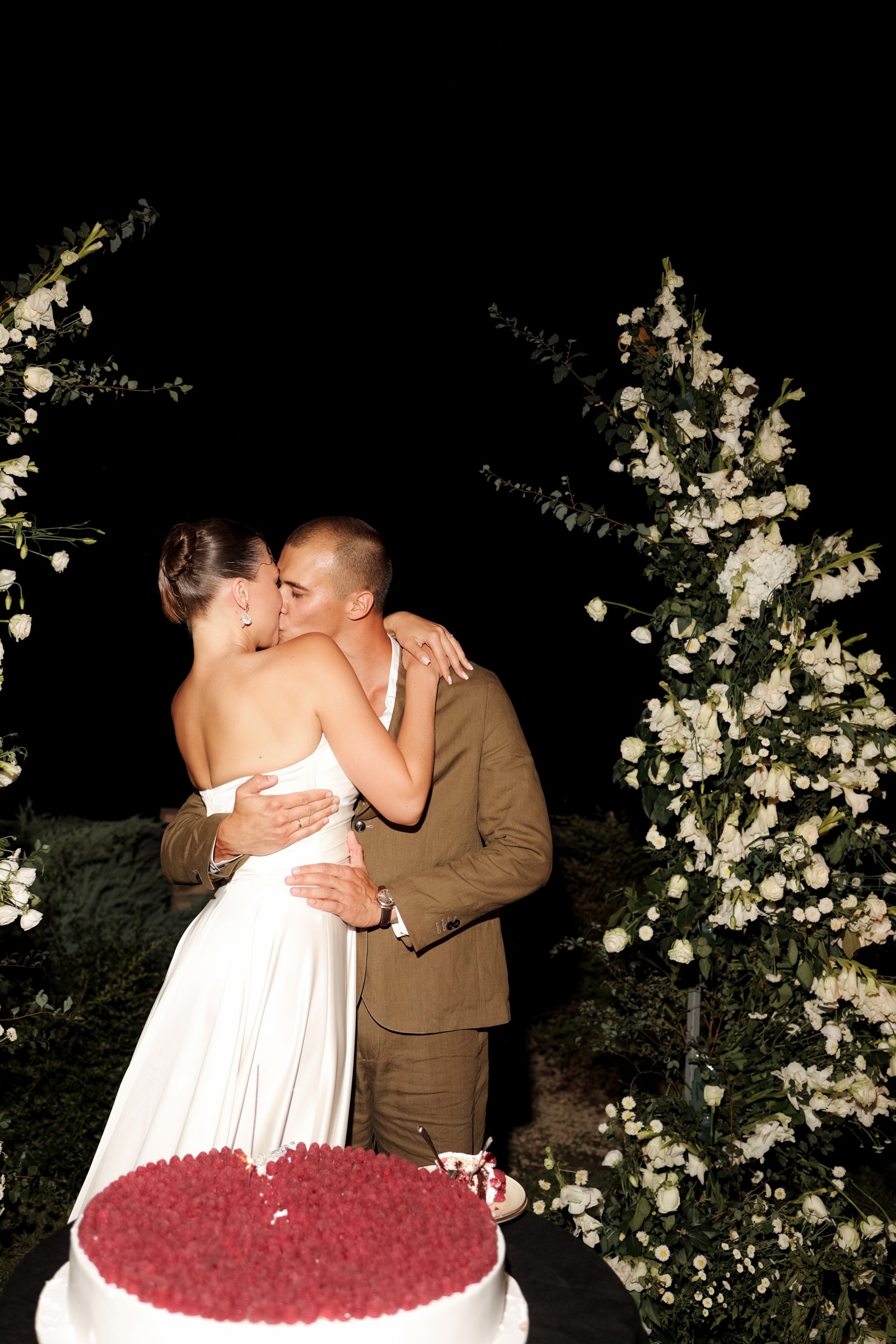Red heart wedding cake by the flower arch at night