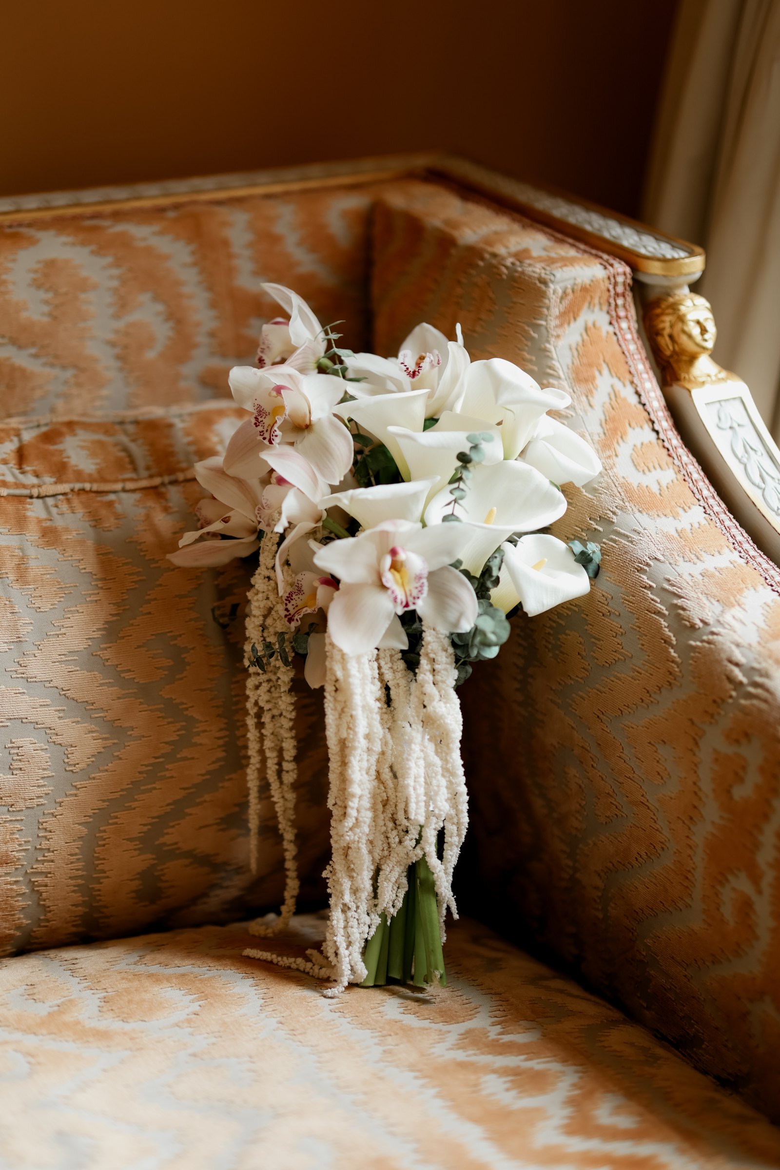 White bridal bouquet resting on a sofa in the palace suite