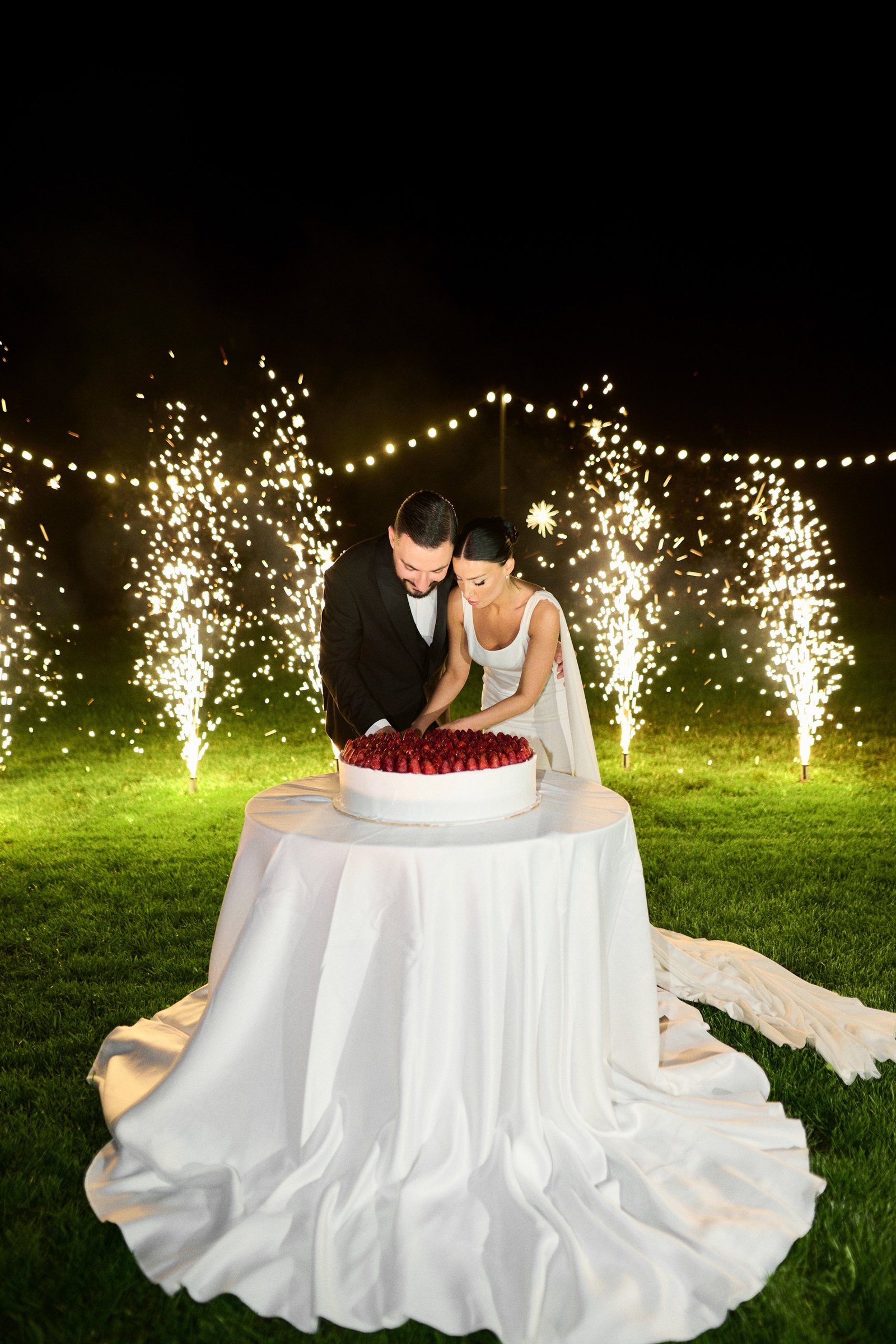 Cutting the cake between cold sparkler fountains at night