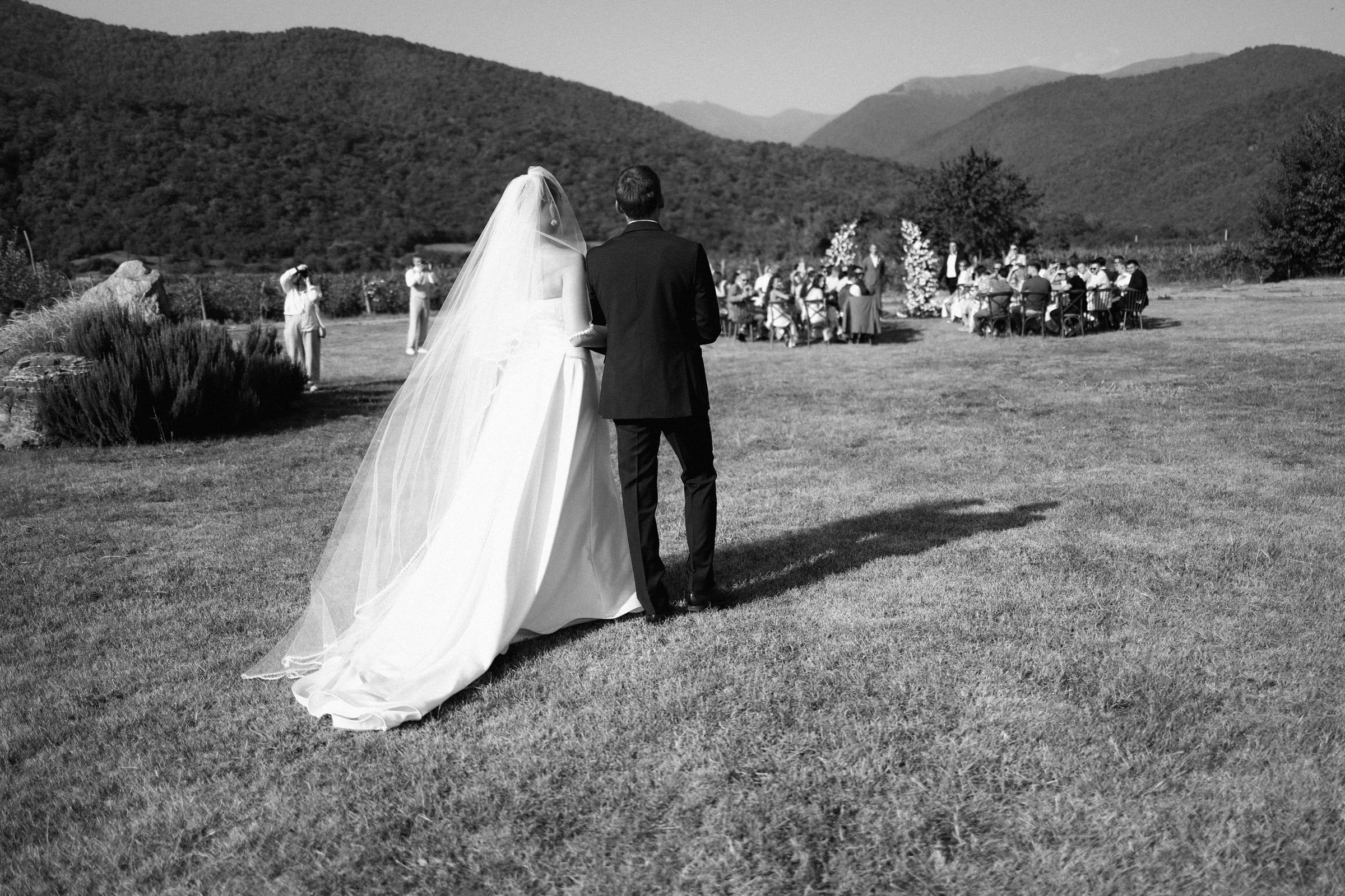 Father walks the bride across the lawn to the open-air ceremony