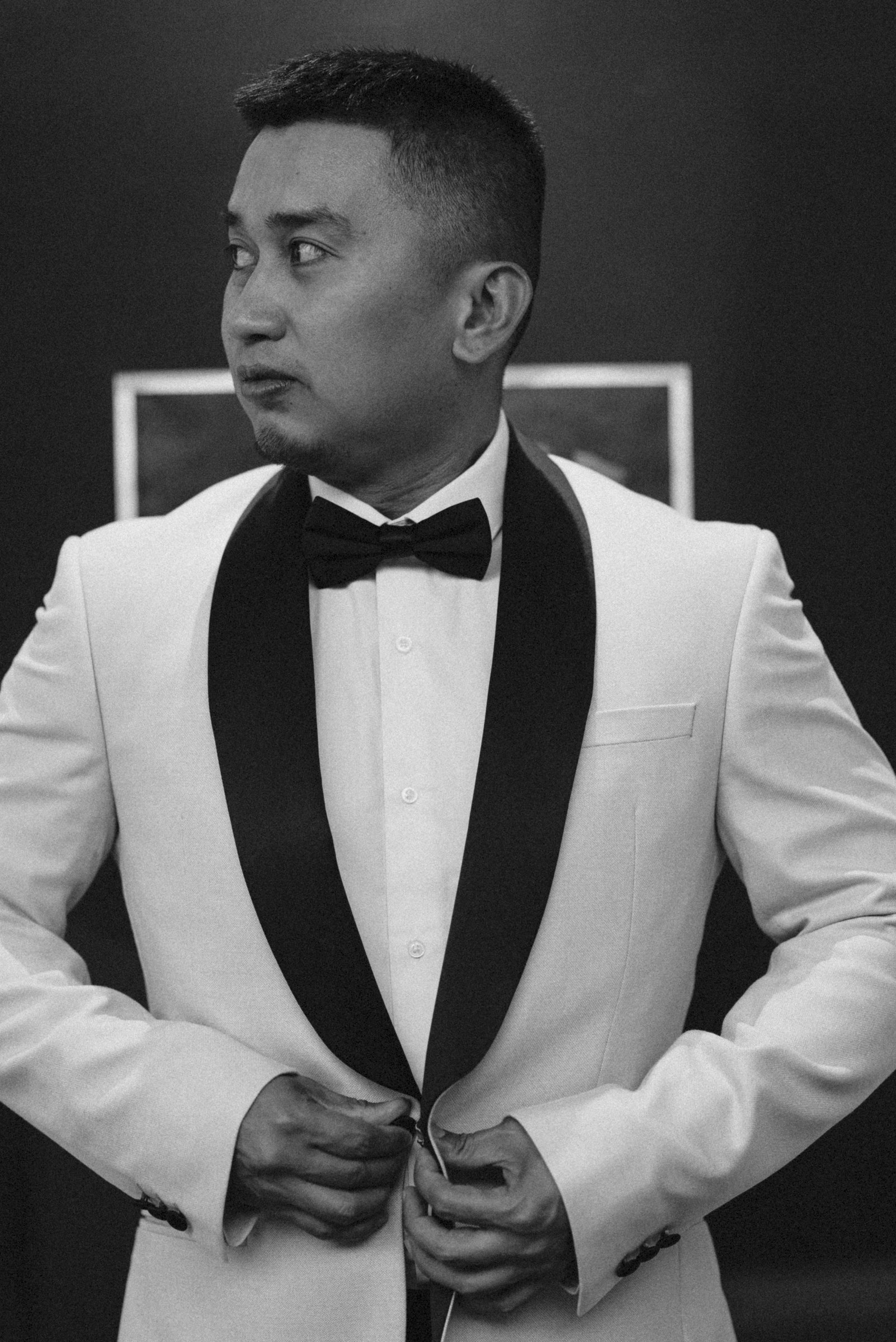 The groom fastens the white dinner jacket, black and white