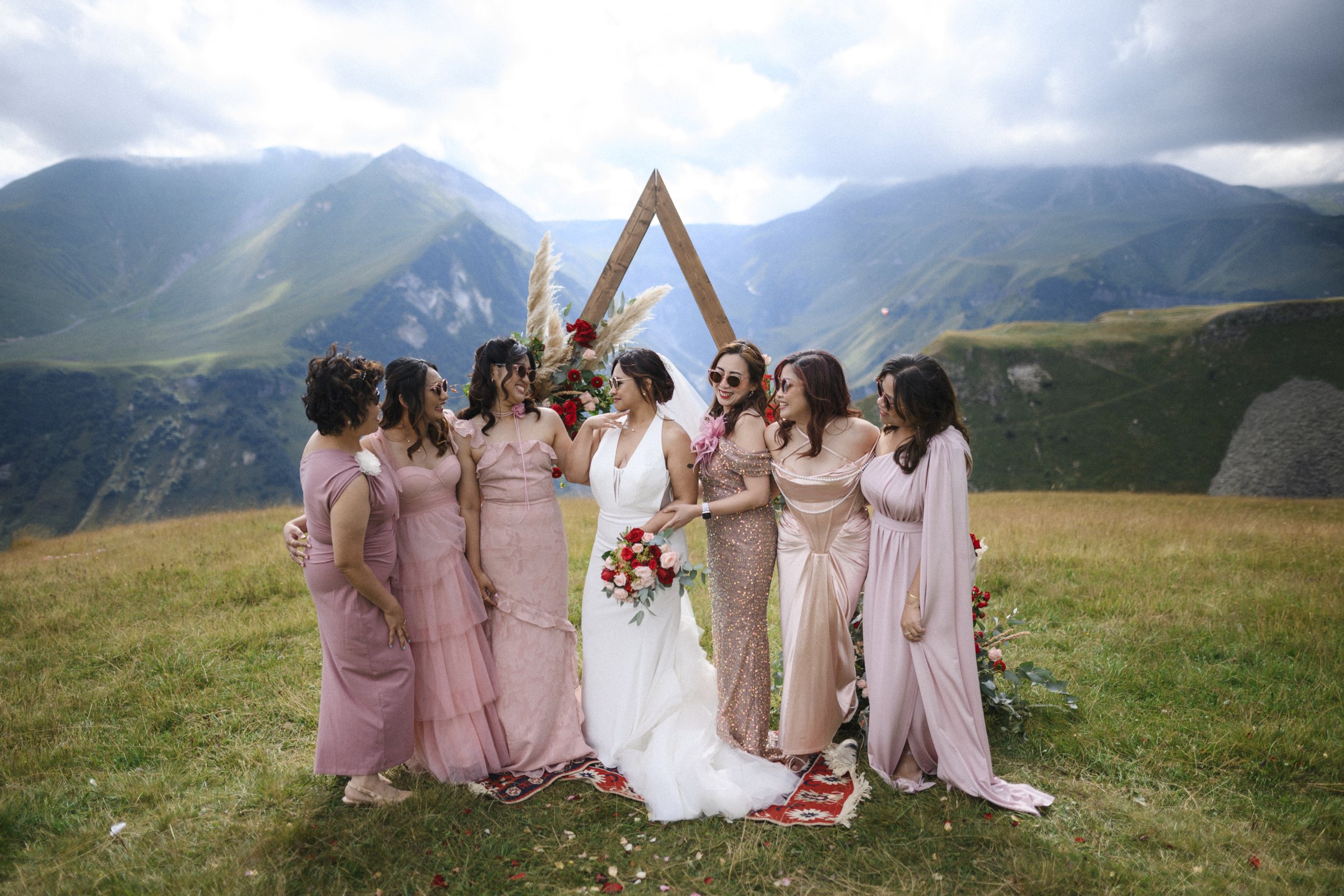 The bridesmaids at the triangle arch, mountains behind