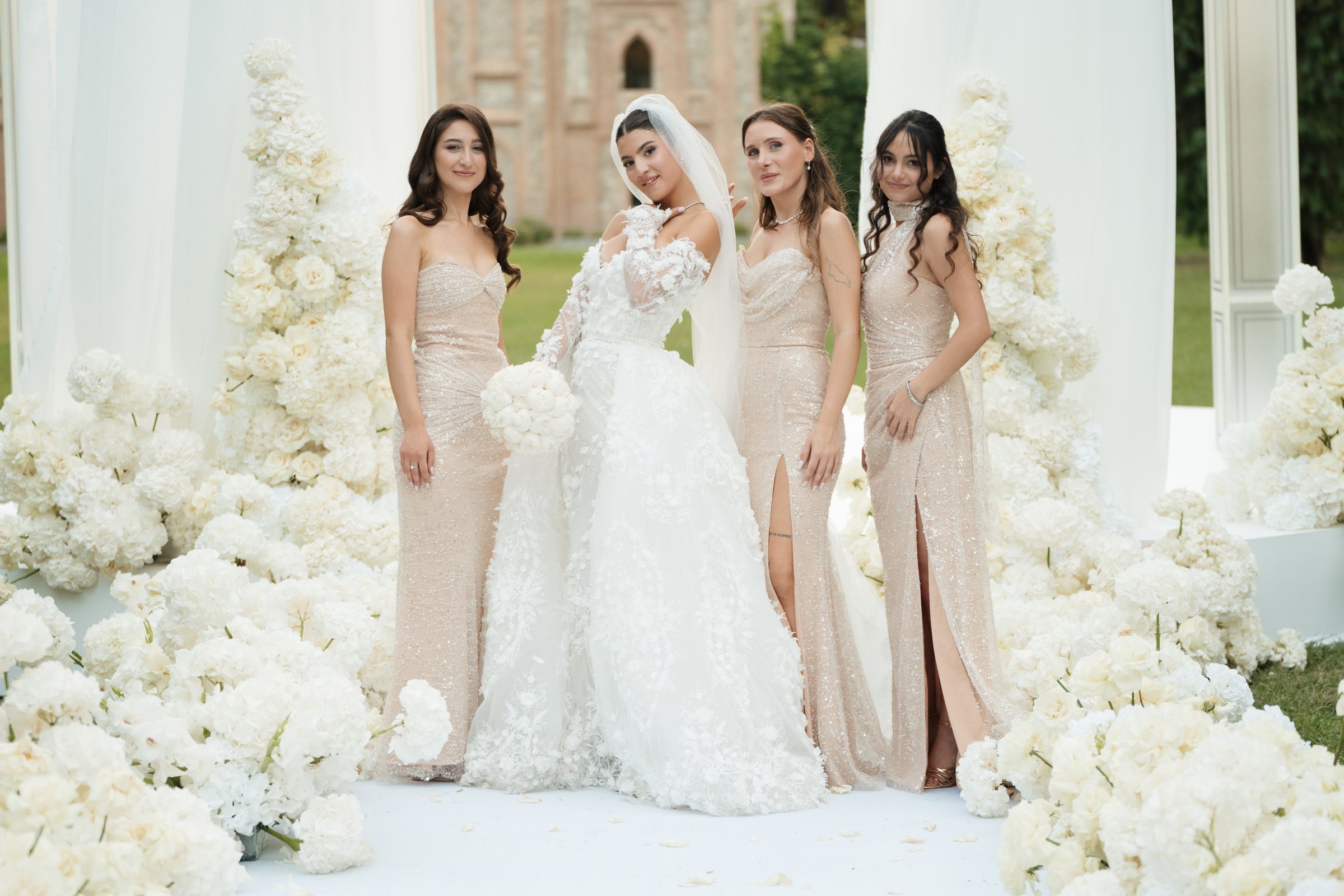 The bride with her bridesmaids against a wall of white flowers