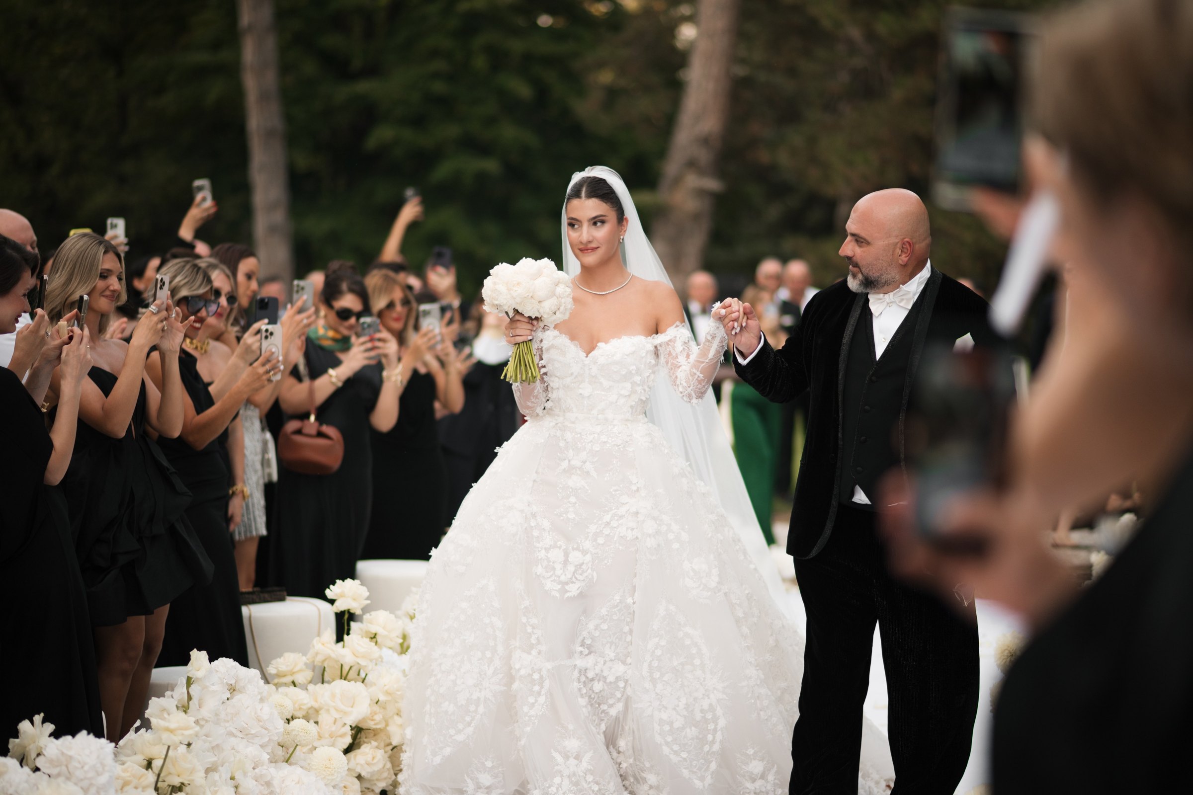 The father walks the bride through the applauding guests