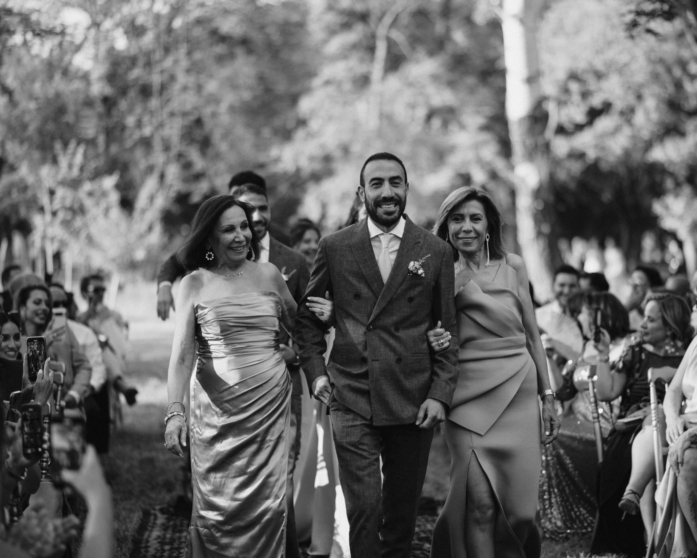 The groom walked in by his parents, black and white