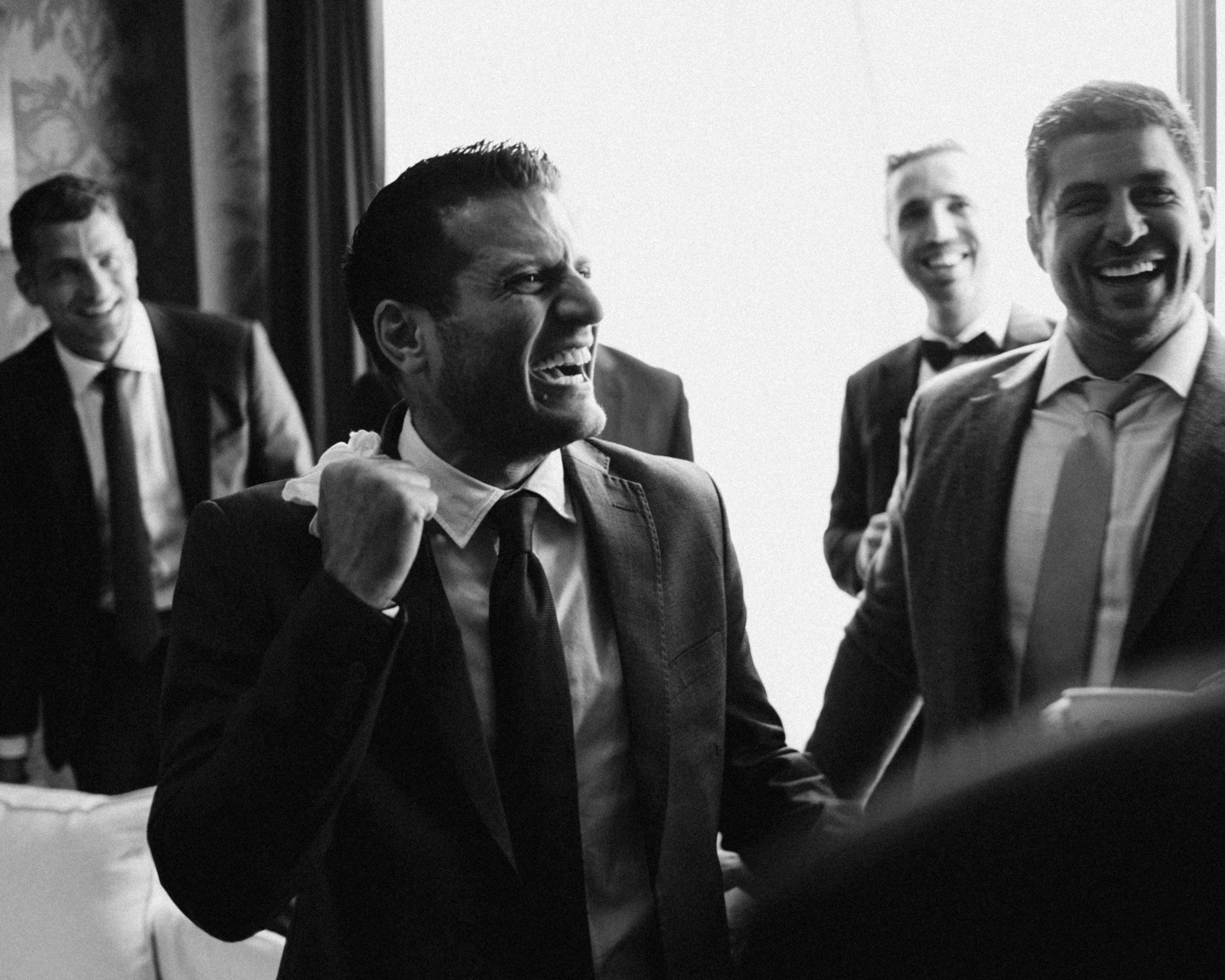 The groomsmen mid-laugh, black and white