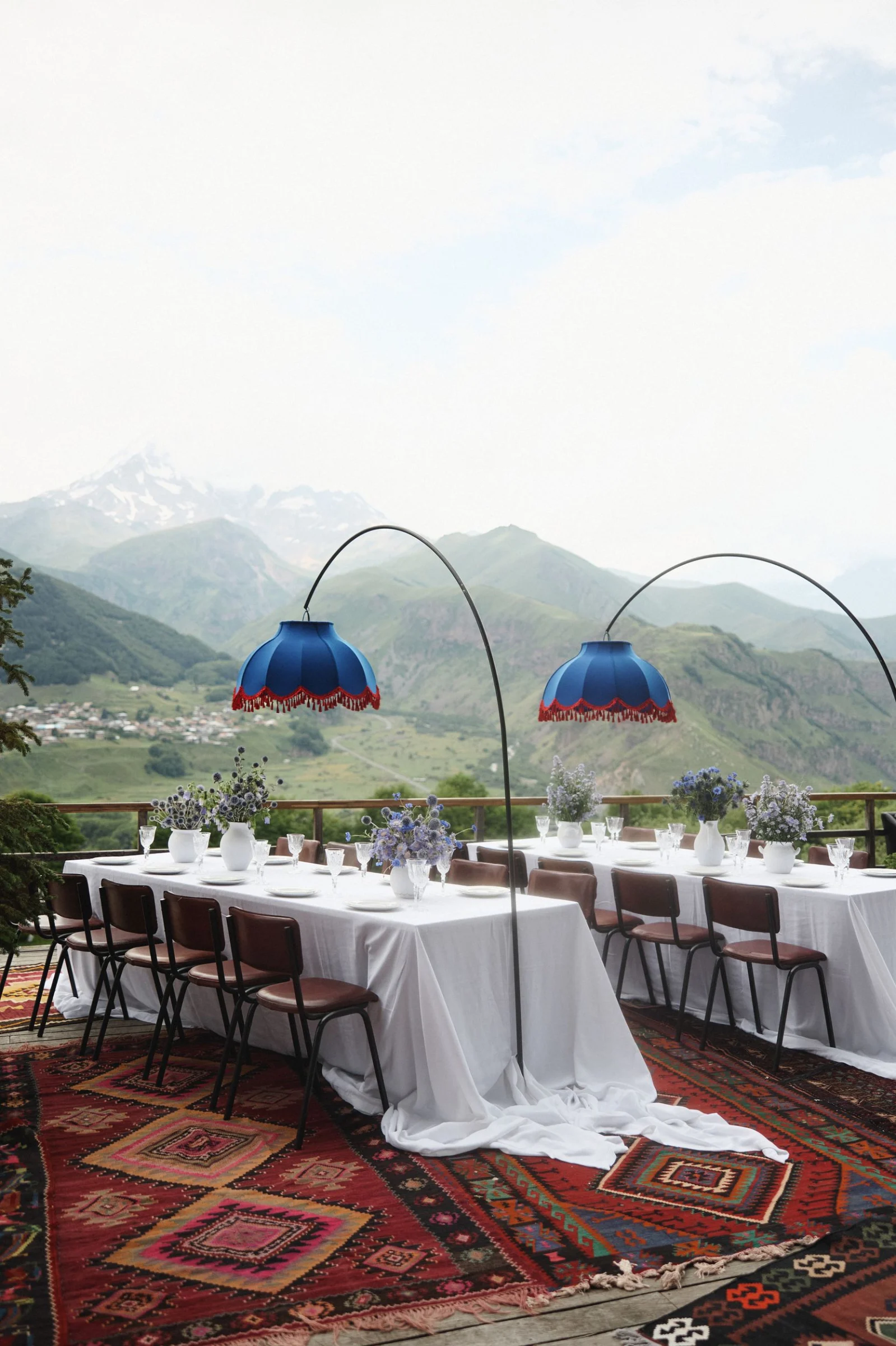 Dinner tables on the terrace under blue lampshades, Kazbek across the valley